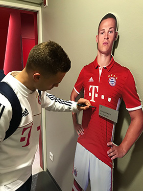 Joshua Kimmich signs his life-size-cut-out figure from the FC Bayern Erlebniswelt