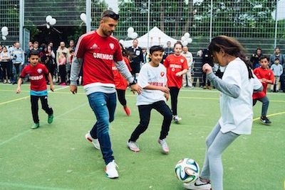 Lukas Podolski spielt Fußball mit Kinder bei einem Event der Lukas Podolski Stiftung